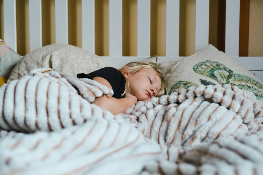 Una bambina dorme sotto una coperta morbida