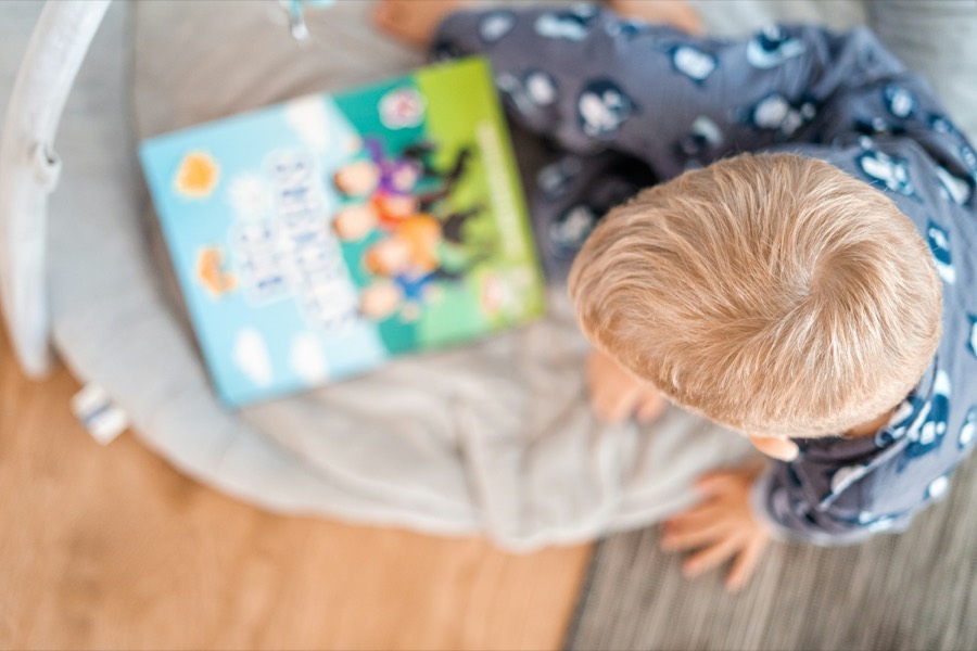 Un bambino in pigiama sfoglia un libro illustrato, visto dall'alto